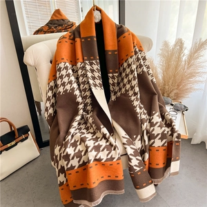 Detail of soft houndstooth scarf in brown and orange draped on a white chair