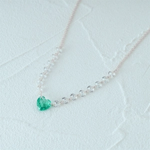 Detailed close-up of a s925 silver necklace featuring a sparkling green heart pendant