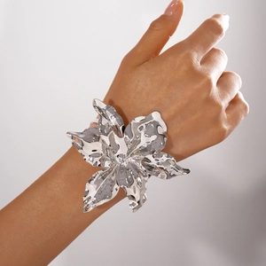 Primo piano dell'ampio bracciale a fascia in argento a forma di fiore su polso femminile