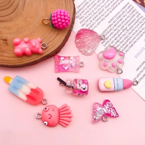 Flat lay of pink DIY resin charms featuring candy, bear, and ice cream shapes with metal rings