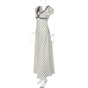 Dettaglio dello scollo a V con pizzo nero sull'abito lungo beige a pois da donna