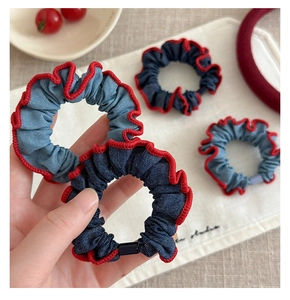 Detailed view of denim scrunchies with red wavy edges and textured fabric folding