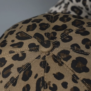 Detailed close-up of leopard print fabric texture and top button on a newsboy cap