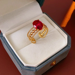 Detailed macro of vintage oval red zircon ring in gold finish on a gray jewelry box
