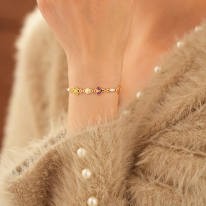 Vintage gold chain bracelet with colorful enamel hearts and pearls on a sweater