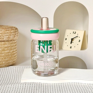 Close-up of glass tea cup with filter net, pink lid and straw on white shelf