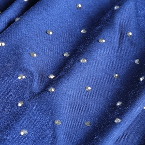 Macro shot of starry blue satin fabric with sparkling rhinestone detail and twill texture