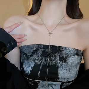 Detailed close-up of a long silver geometric pendant necklace worn by a fashion model