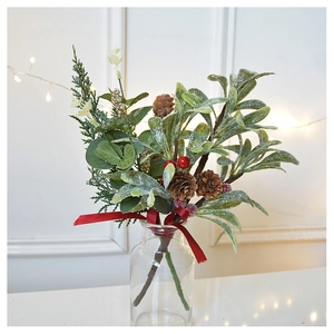 Close-up of frosted Christmas berries with pine cones and red ribbon in a glass vase