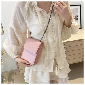 Detail of a minimalist pink crossbody phone bag with black metal chain and fine stitching