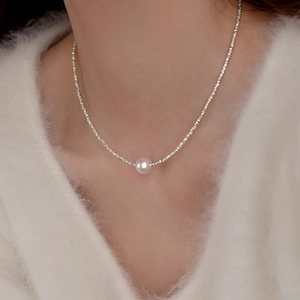 Elegant pearl necklace with irregular silver beads on a model wearing white knitwear