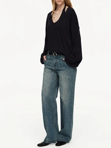 Detail of a black V-neck long-sleeve top paired with high-waist wide-leg blue jeans