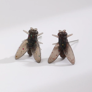 Dettaglio macro di orecchini a forma di mosca in resina traslucida con glitter colorati
