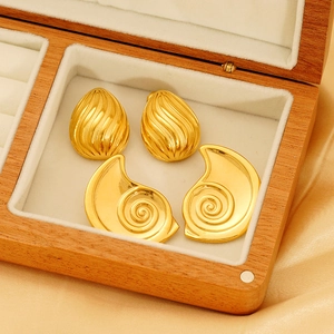 Boucles d'oreilles dorées en forme de goutte et spirale dans un coffret en bois de luxe