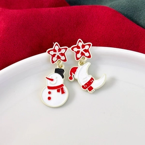 Macro view of Christmas snowman and moon earrings with festive red snowflake details