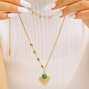 Elegant gold necklace with green emerald pendant and sunburst detail worn on neck
