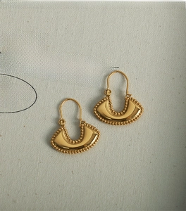 Detail shot of vintage French style gold-plated handbag-shaped earrings on white fabric