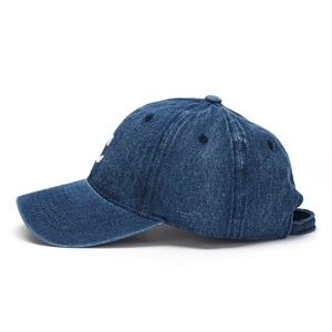 Close-up of white embroidered C letter on dark blue washed denim baseball cap