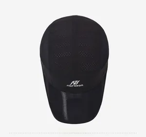 Top view of black quick-dry sports cap showing breathable laser-cut holes and mesh fabric