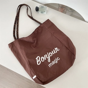 Detail of dark brown nylon tote bag with leopard print strap and Bonjour Magic print