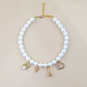 Detail of white pearl pet necklace with gold deer, crown, tower and heart pendants