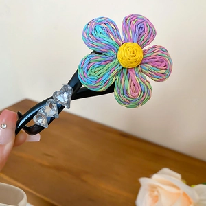 Détail d'une pince à cheveux à fleurs tissées avec des breloques de cœurs en cristal