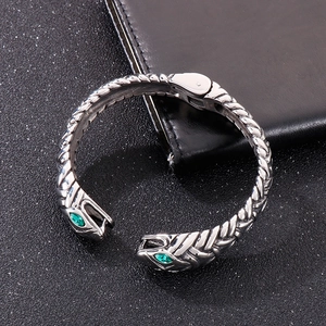 Macro view of double-headed snake open cuff bracelet with green crystal eyes