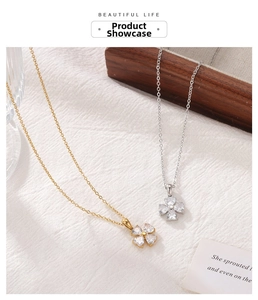 Detailed view of silver and gold clover necklaces with heart-shaped crystals on fabric