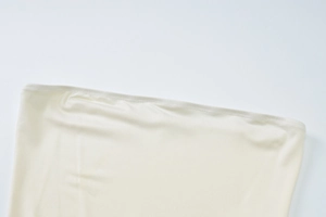 Detail of off-white off-shoulder dress featuring pleated mesh and smooth silky fabric