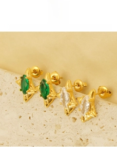 Detailed view of 18k gold star earrings with marquise emerald cubic zirconia on white stone