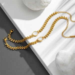 Gold stainless steel wheat chain bracelet with heart shell pendant in soft natural lighting