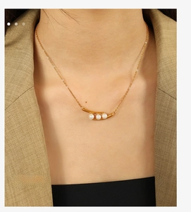 Détail de trois perles blanches sur chaîne dorée portée avec un blazer marron chic