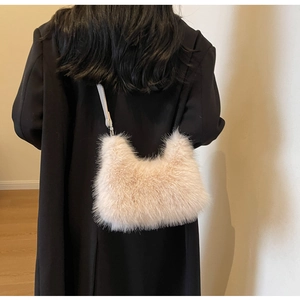 Detail of soft cream faux fur shoulder bag worn on a black coat for a winter look