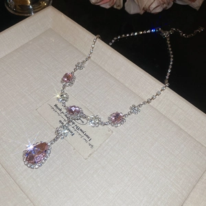 Macro view of pear-shaped pink gemstone necklace with silver floral chain and diamonds