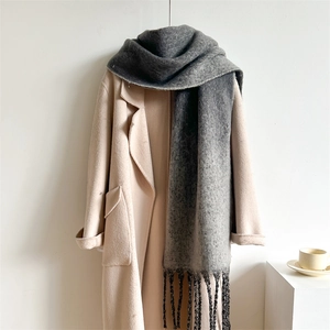 Detail of grey gradient scarf with soft fringes styled on a beige winter coat