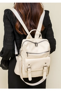 Fashionable off-white soft leather backpack showing layered pockets and buckle details on model