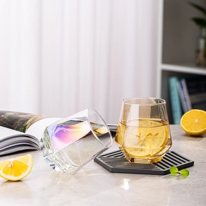 Close-up of geometric hexagonal glasses in iridescent and amber glass with lemon water