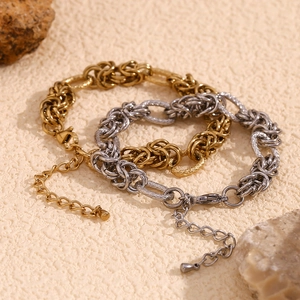 Minimalist geometric 14K gold and silver knot chain bracelets on a textured background