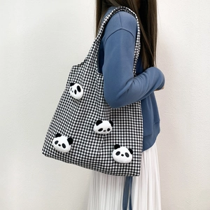 Detail of checkered canvas tote bag with 3D panda plush dolls on a blue sweatshirt
