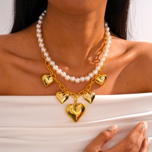 Detail of double-layer necklace with white pearls and five golden heart charms