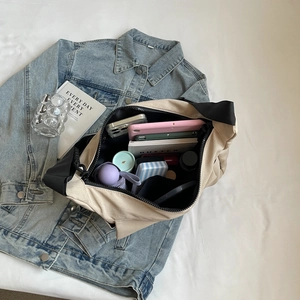 Large beige nylon tote bag with high capacity storage shown on a blue denim background