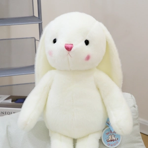 Close-up of a cute white long-eared bunny plush toy sitting on a soft light cushion