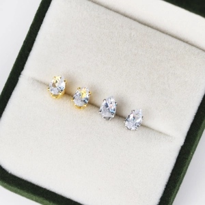 Macro shot of gold and silver teardrop zircon earrings in a velvet jewelry gift box