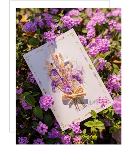 Detail of handmade greeting card with purple dried flowers and a twine bow decoration