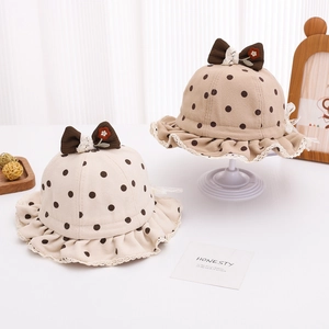 Détail de chapeaux seau bébé à pois avec nœuds et bords en broderie de dentelle fine