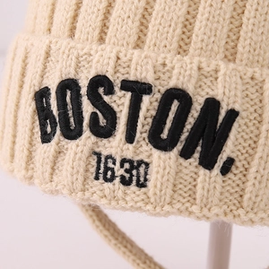 Detailed view of cream knit beanie featuring black 3D embroidered Boston lettering