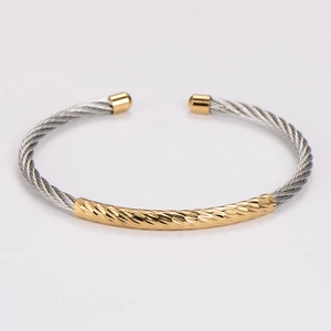 Detail view of two-tone stainless steel cable bangle with 18K gold plated geometric accents