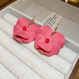 Close-up of pink flower earrings with golden hooks in a velvet jewelry box