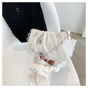 Detail of white pleated handbag featuring floral embossed fabric and silver plum chain
