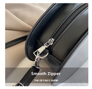 Detail of a black PU leather crossbody bag showing the smooth silver zipper and D-ring buckle